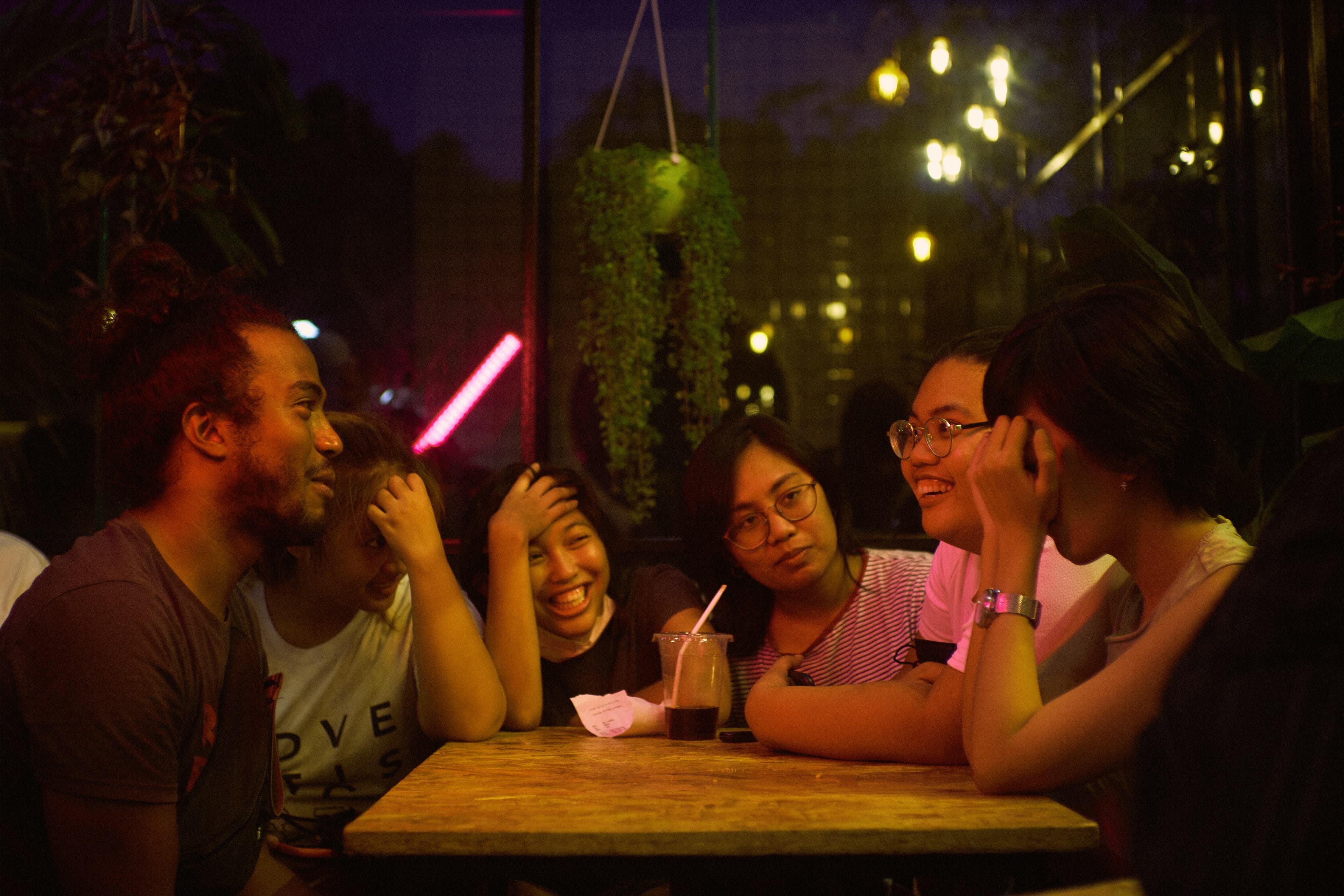 A mixed group laughing around a table under purple bar lighting