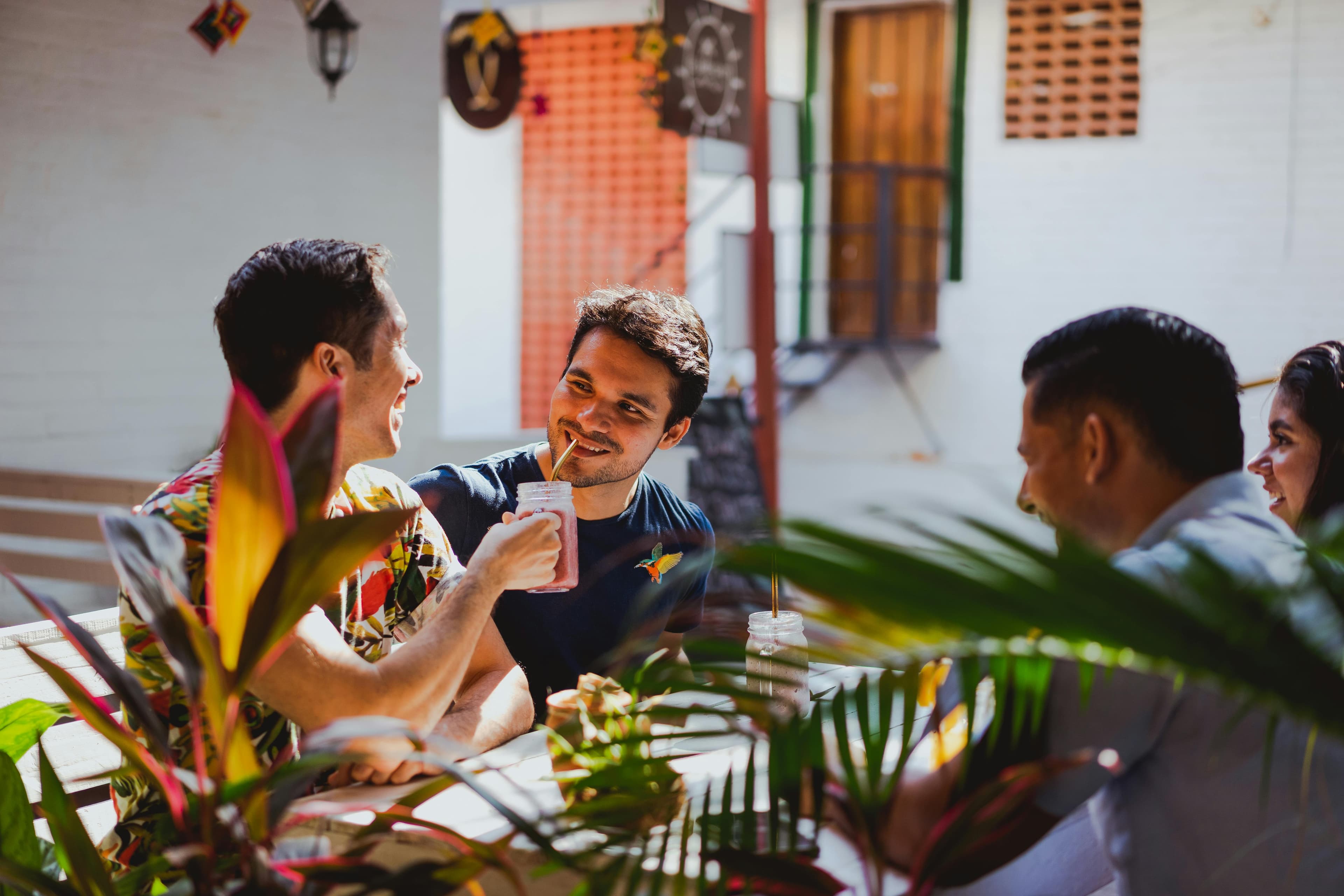 Friends mid-conversation around a sunlit terrace table on holiday