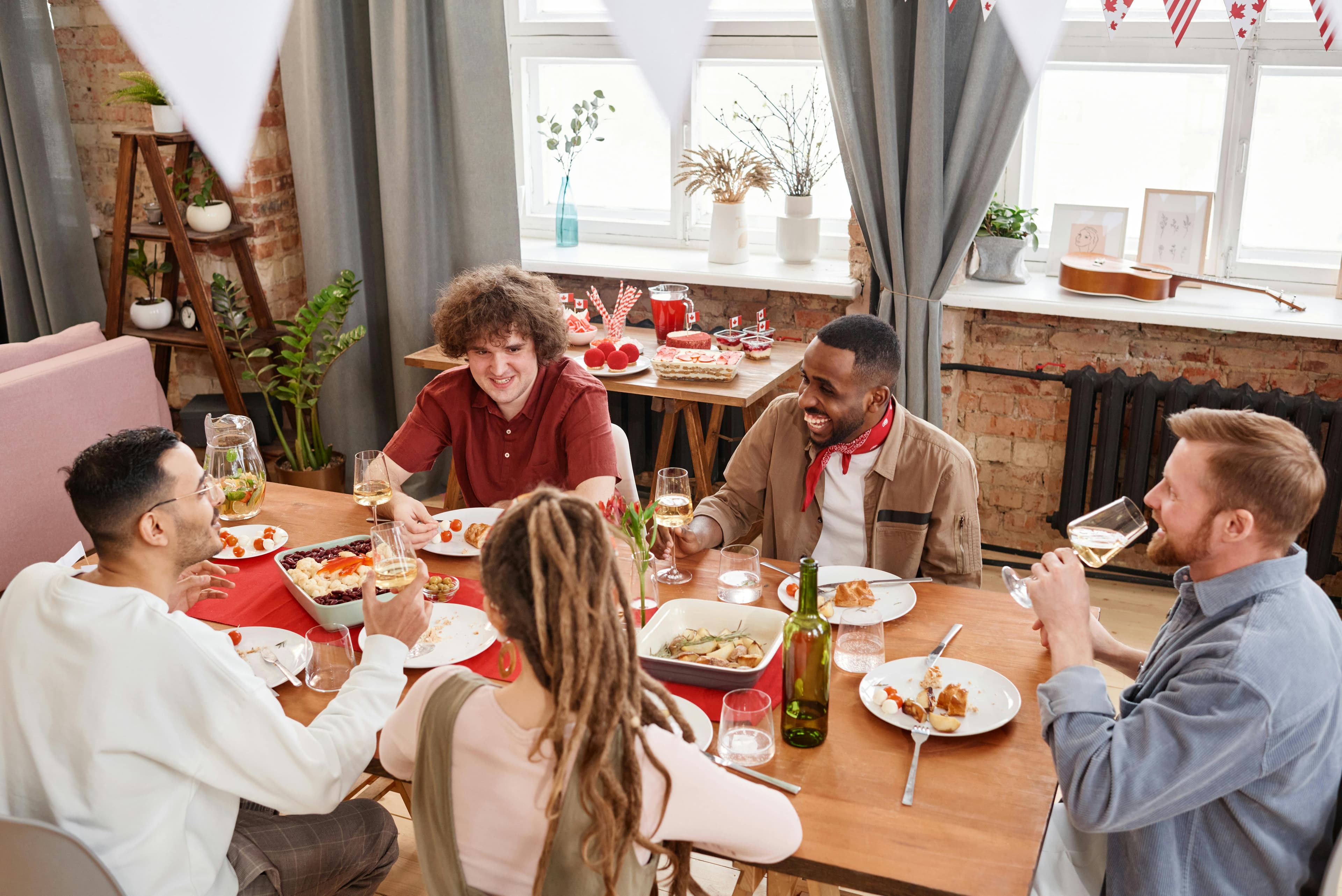 A long dinner table at a flat with bunting strung above and shared dishes